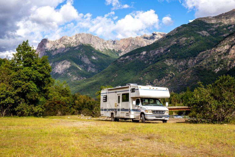 Motorhome parked in a scenic mountain landscape surrounded by greenery during an RV trip